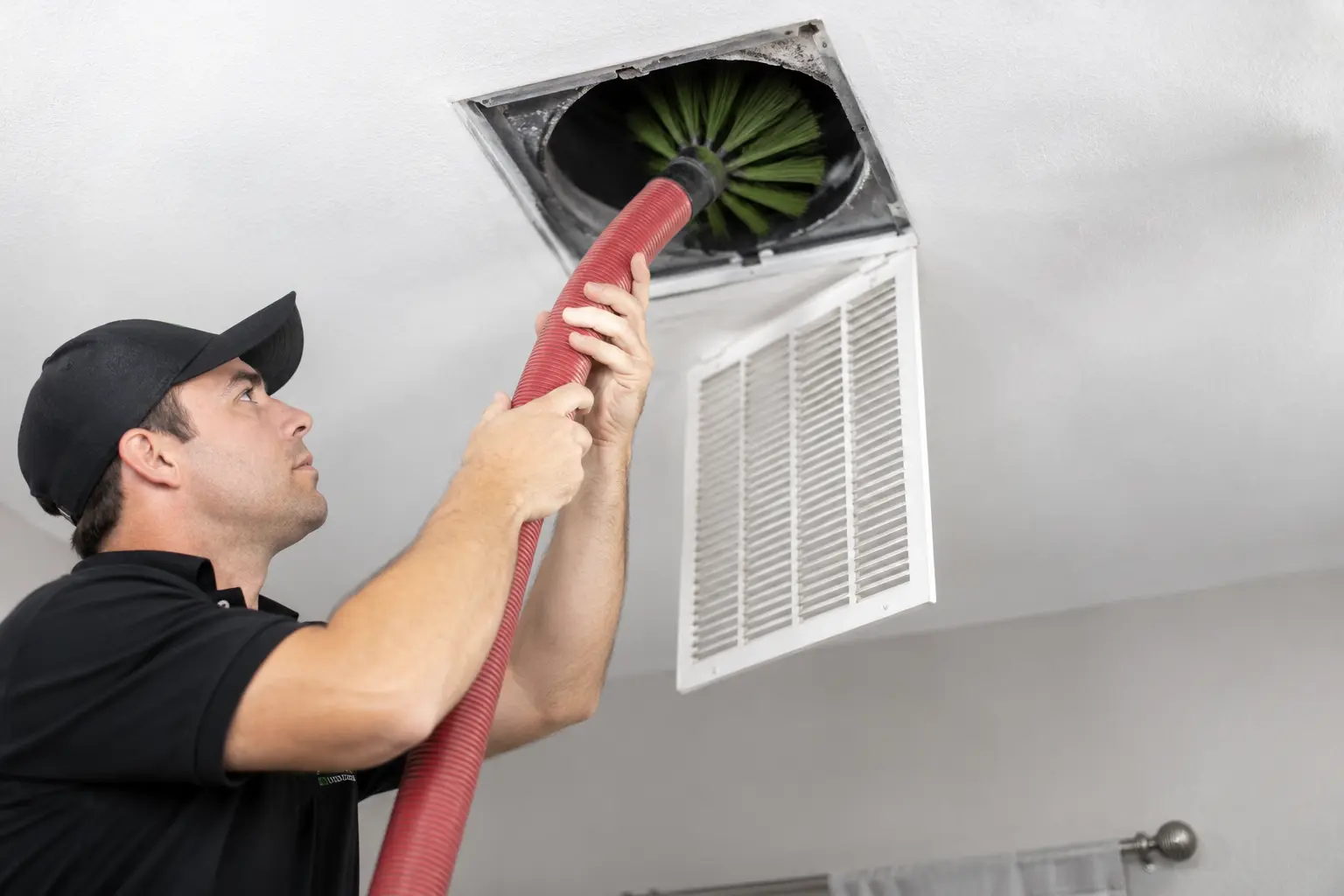 Professional technician cleaning a residential air duct with specialized equipment